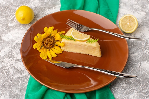 Вид сверху маленький вкусный торт с лимоном внутри коричневой тарелки на светлом фоне сладкое тесто для торта