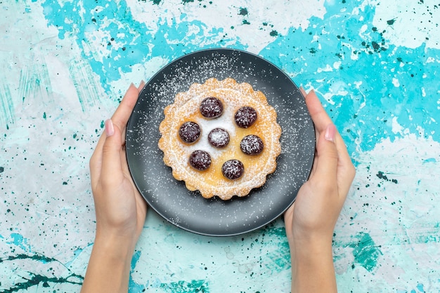 Top view little delicious cake with sugar powder and fruits inside plate on the light blue table cake fruit sweet bake