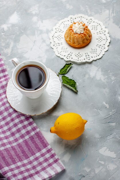 Top view little delicious cake with tea and sour lemon on the light desk cake biscuit sweet biscuit cookie