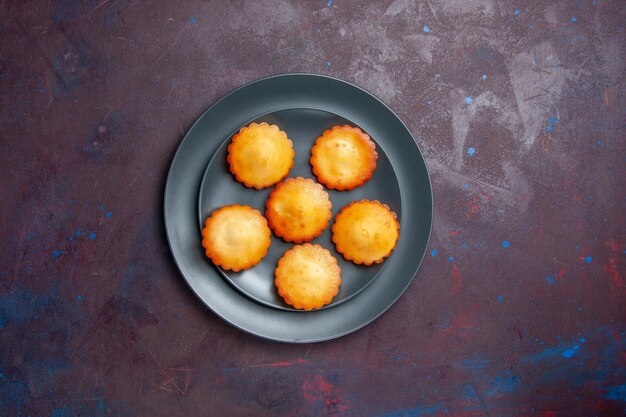 Top view little delicious cakes inside plate on dark surface pie biscuit cake sweet tea sugar cookie