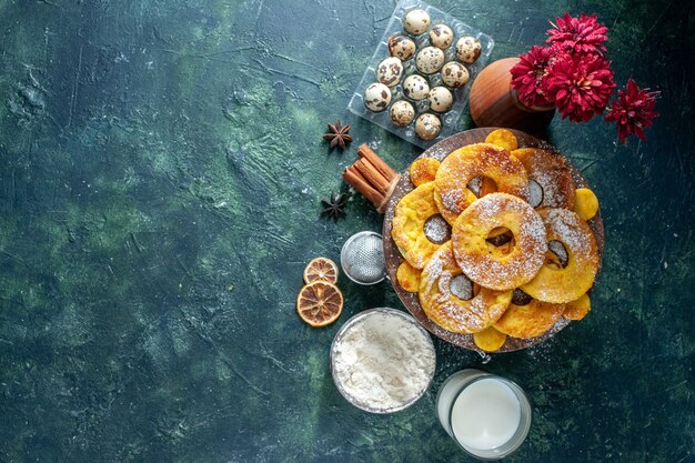 Top view little delicious cakes in pineapple ring shape with milk on dark background hotcakes bake pie cookie cake fruit pastry free space