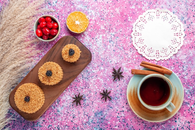 Top view of little delicious cakes round formed with cinnamon and tea on the pink surface