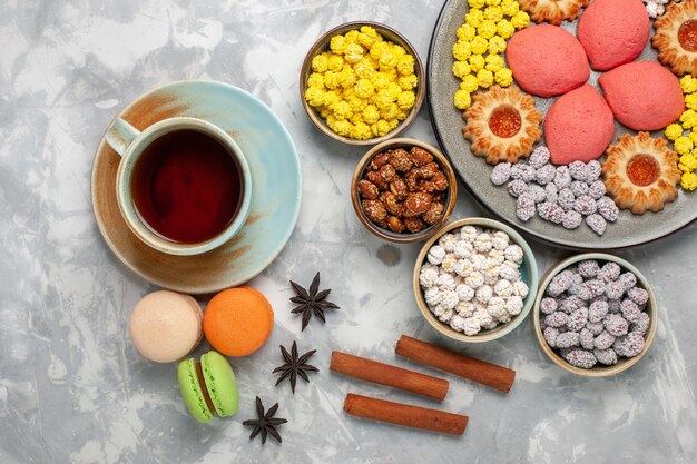 Top view little delicious cakes with cookies tea and candies on white surface candy sweet biscuit cake pie sugar pie