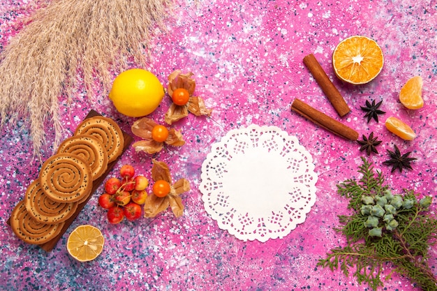 Vista dall'alto di piccoli deliziosi biscotti con limone e cannella sulla superficie rosa chiaro