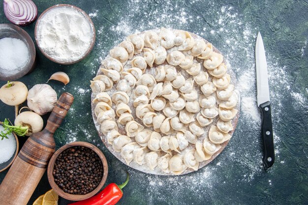 Top view little dumplings with flour and vegetables on a dark background meat dough food dish color vegetable meal