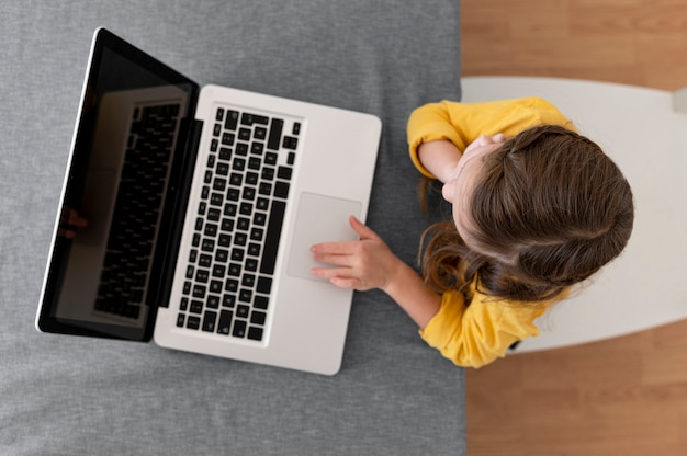 Free photo top view of little girl using laptop