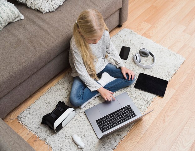 Top view of little girl with gadgets on floor