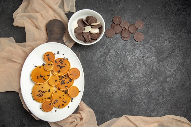Top view little pancakes with cookies on dark-grey floor sweet cake milk