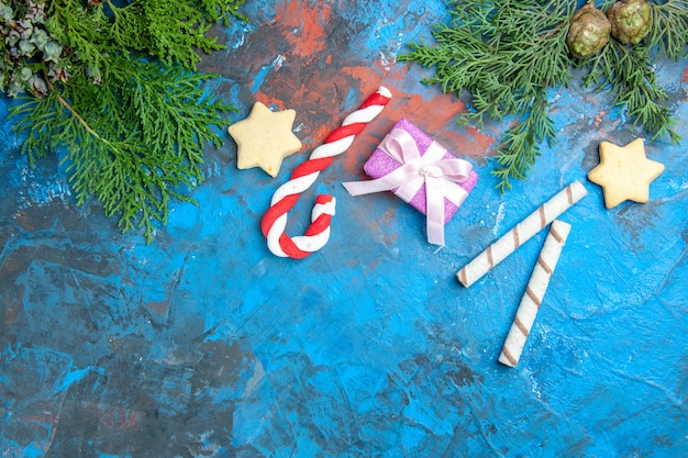 Top view of little presents with candies on blue surface