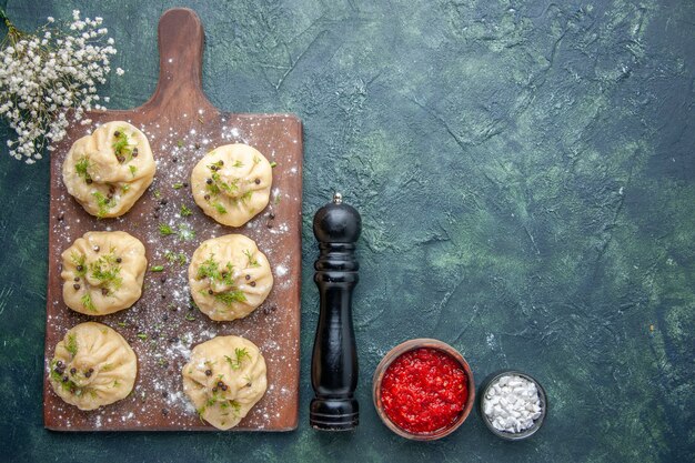 Top view little raw dumplings with meat inside on dark-blue surface meat dough cuisine dish cake dinner cooking