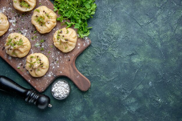 Top view little raw dumplings with tomato sauce and greens on a dark blue surface cooking dinner dough dish meal cuisine meat