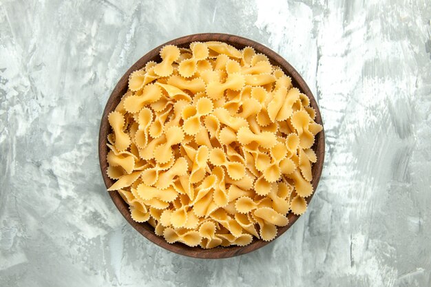 Top view little raw pasta inside plate on light background