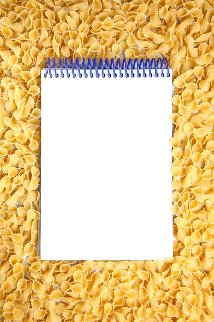 Top view little raw pasta with notepad on light background