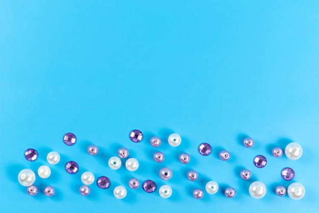 A top view little round buttons colored jewellery details isolated on blue, diamond color jewels