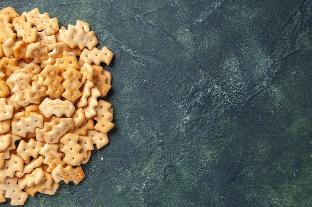 Top view of little salted crackers on dark surface