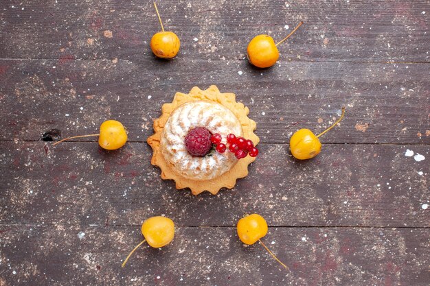 Top view little simple cake with sugar powder raspberry and cranberries yellow cherries on the brown wooden rustic background berry fruit cake sweet bake