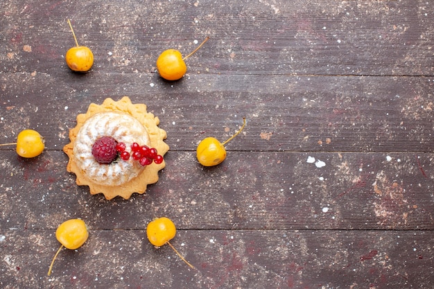 Top view little simple cake with sugar powder raspberry and cranberries yellow cherries on the brown wooden rustic desk berry fruit cake sweet bake