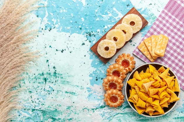 上面図クラッカー乾燥パイナップルリングと水色の背景にクッキーが付いた小さなスパイシーなチップススナックカラークリスプカロリー