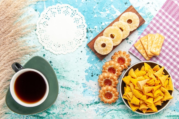 Top view little spicy chips with crackers dried pineapple rings and cookies on light blue desk chips snack color crisp calorie