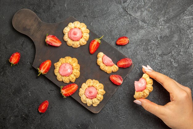 Top view of little sugar cookies with strawberry cream on grey surface