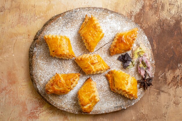 Top view of little sweet pastries for tea on light desk