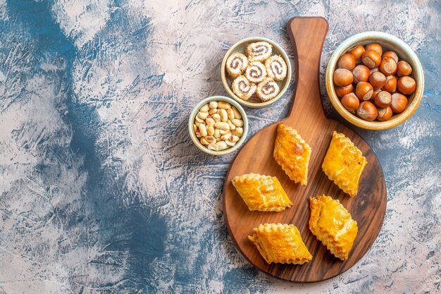 Top view of little sweet pastries with nuts on blue surface