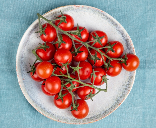 Foto gratuita vista dall'alto di piccoli pomodori nel piatto sulla superficie blu