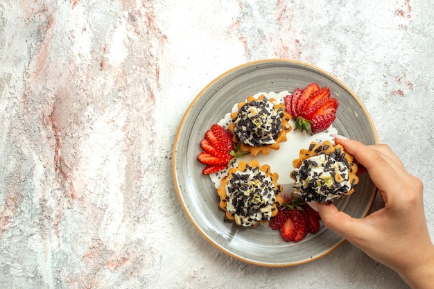 Free photo top view little yummy cakes with strawberries on white surface birthday celebration sweet biscuit cake cookie