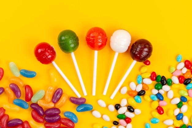 A top view lollipops and candies colored sweet isolated on yellow, sugar sweet confectionery