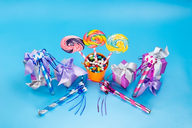 Вид сверху леденцы на палочке и подарки алогн с разноцветными конфетами свистки на день рождения на синем фоне конфеты сладкий сахарный конфитюр