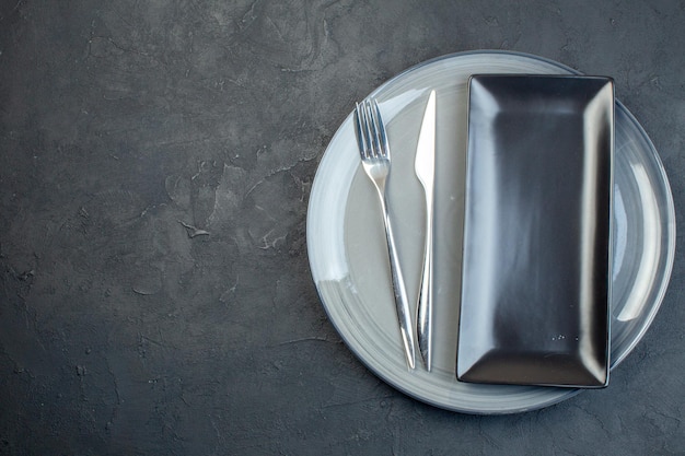 어두운 배경 가로 다채로운 여성용 칼 유리 음식에 포크와 회색 접시가 있는 위쪽 보기 긴 검은색 접시
