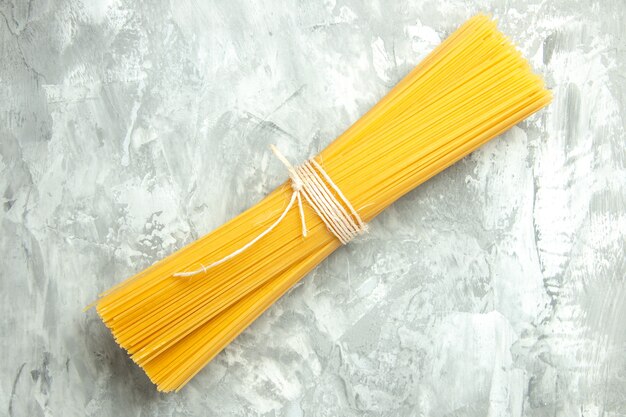 Вид сверху длинная итальянская паста в сыром виде, перевязанная на светлом фоне