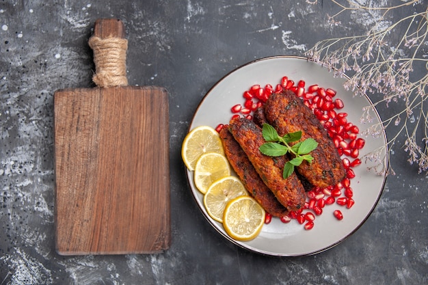 Top view long meat cutlets with lemon and pomegranates