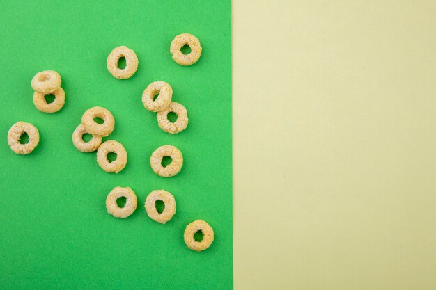 Top view of loop and healthy cereals on green surface and yellow background