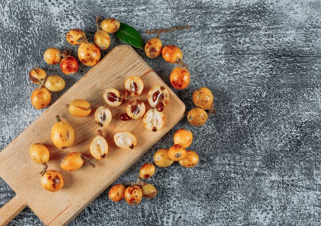 Loquat di vista superiore sul tagliere su sfondo grigio con texture. spazio orizzontale per il testo