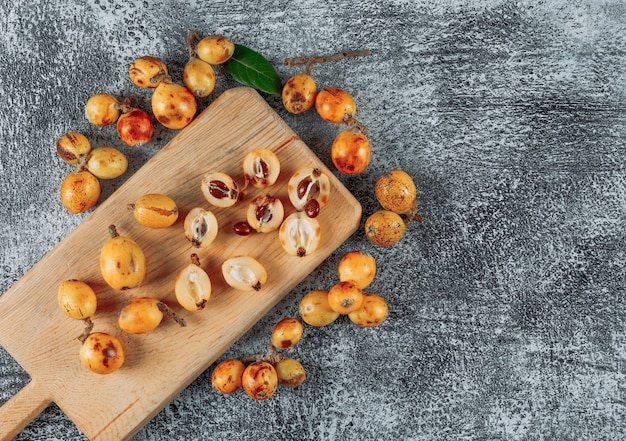 Top view loquats on cutting board on gray textured background. horizontal space for text