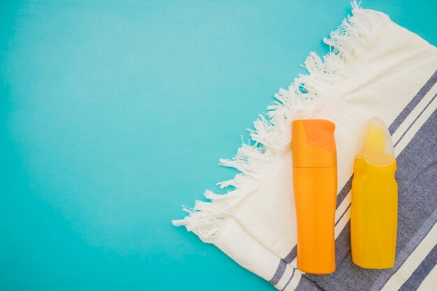 Top view of lotions and towel on blue surface