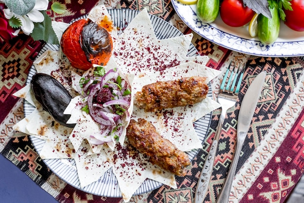 Top view lula kebab on pita bread with eggplant and tomato grilled with onions