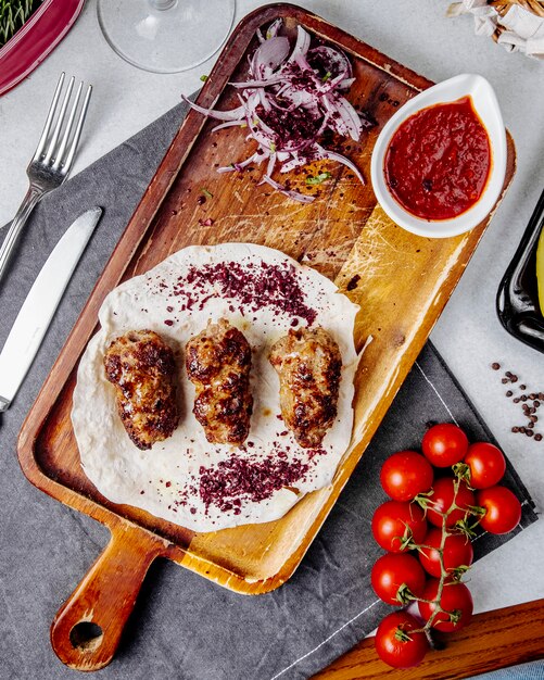 Top view of lule kebab with red onions on a wooden board