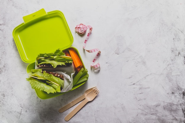 Top view of lunch box with measuring tape and cutlery