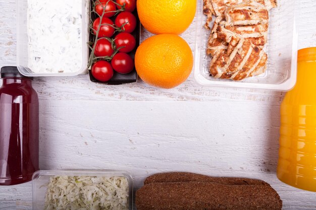 Over top view of lunch packed in different boxes. Fresh and healthy eating on wooden background