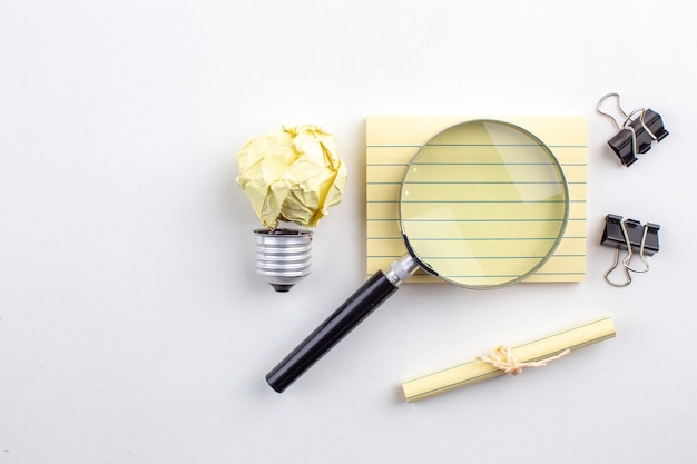 Free photo top view lupa on sticky note binder clips rolled up paper tied with rope on white table