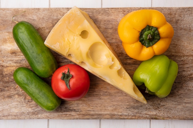 Free photo top view maasdam cheese with cucumbers  tomato and bell peppers on a stand