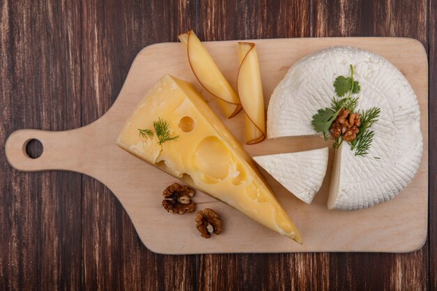 Foto gratuita vista dall'alto maasdam e formaggio feta con noci su un supporto su uno sfondo di legno