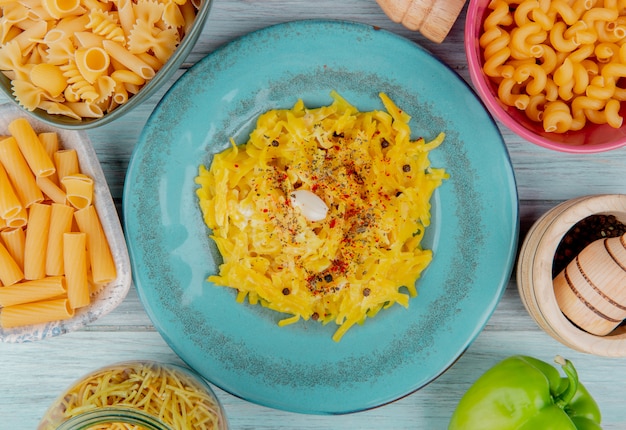 Top view of macaroni pasta in plate surrounded by raw pasta