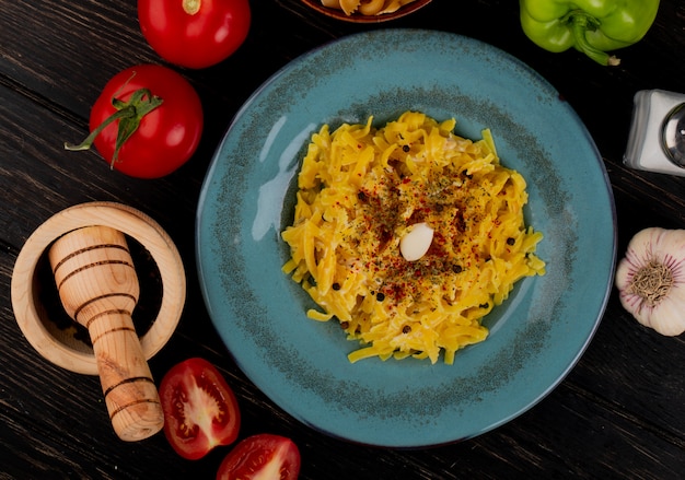 Vista dall'alto di maccheroni pasta nel piatto con pomodori interi e tagliati