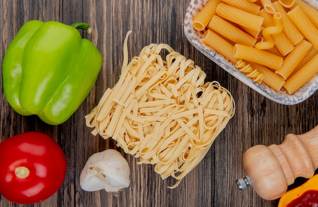 Top view of macaronis as tagliatelle ziti with pepper garlic tomato salt on wood