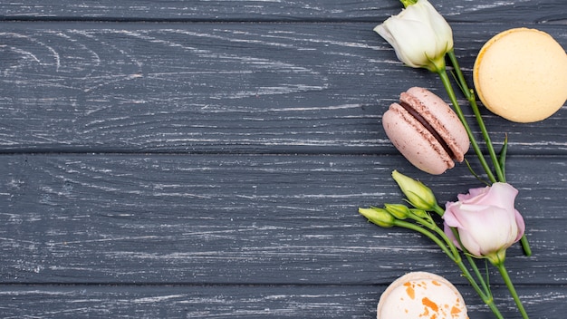 Foto gratuita vista dall'alto di macarons con rose e copia spazio