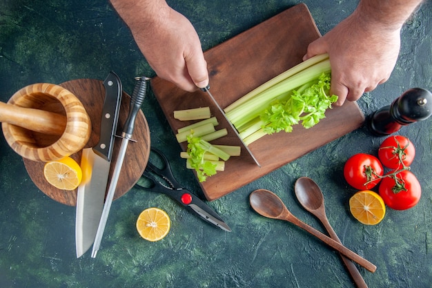 Вид сверху мужского повара, режущего сельдерей на темном столе, салат, диетическое питание, цветное фото, еда, здоровье