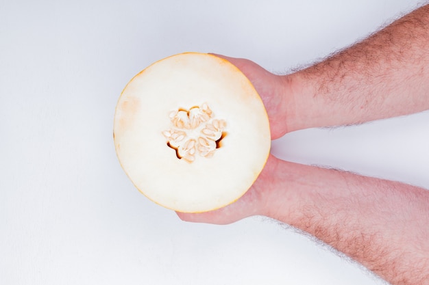 Top view of male hands holding melon on white background with copy space